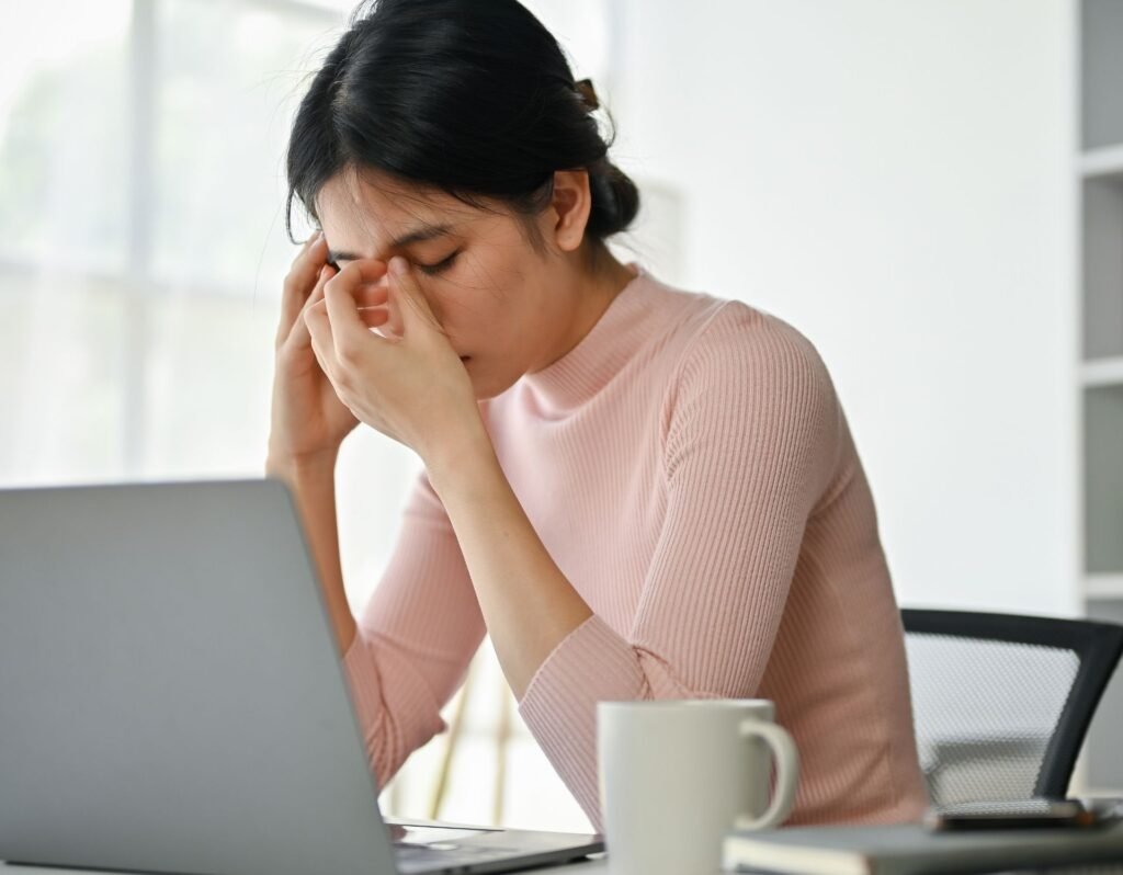 stressed/overwhelmed woman working a side hustle from home on a laptop