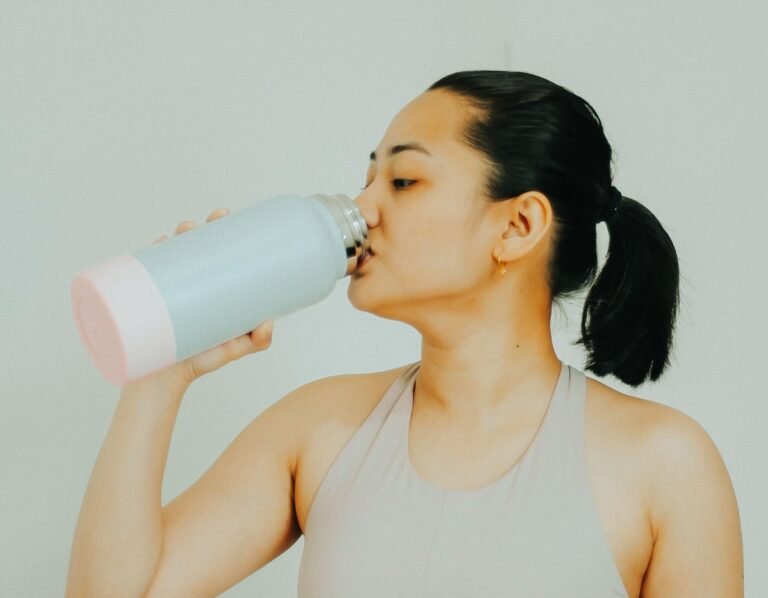 woman drinking from water bottle with electrolytes