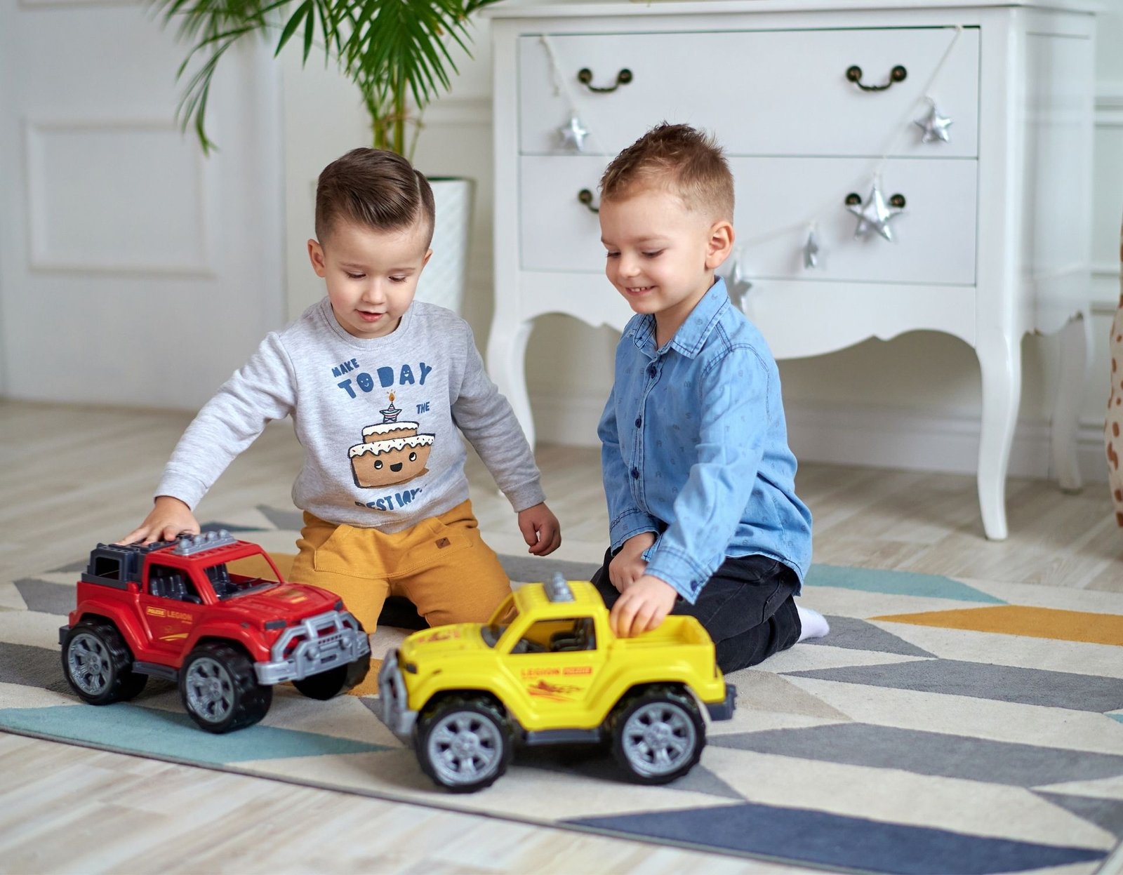 two toddler boys playing with trucks in a clean and organized playroom