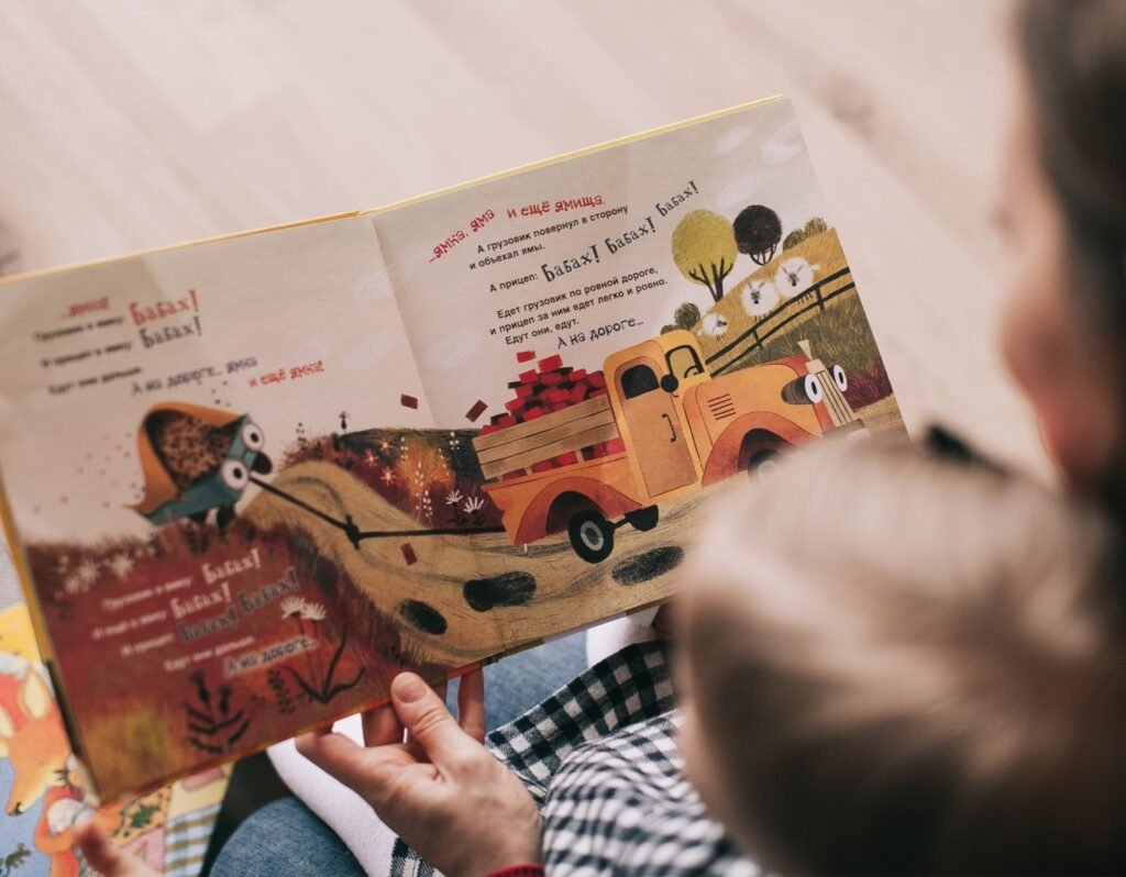 mom and toddler reading a picture book. mom and son are blurred, focus is on the pages of a childs picture book.