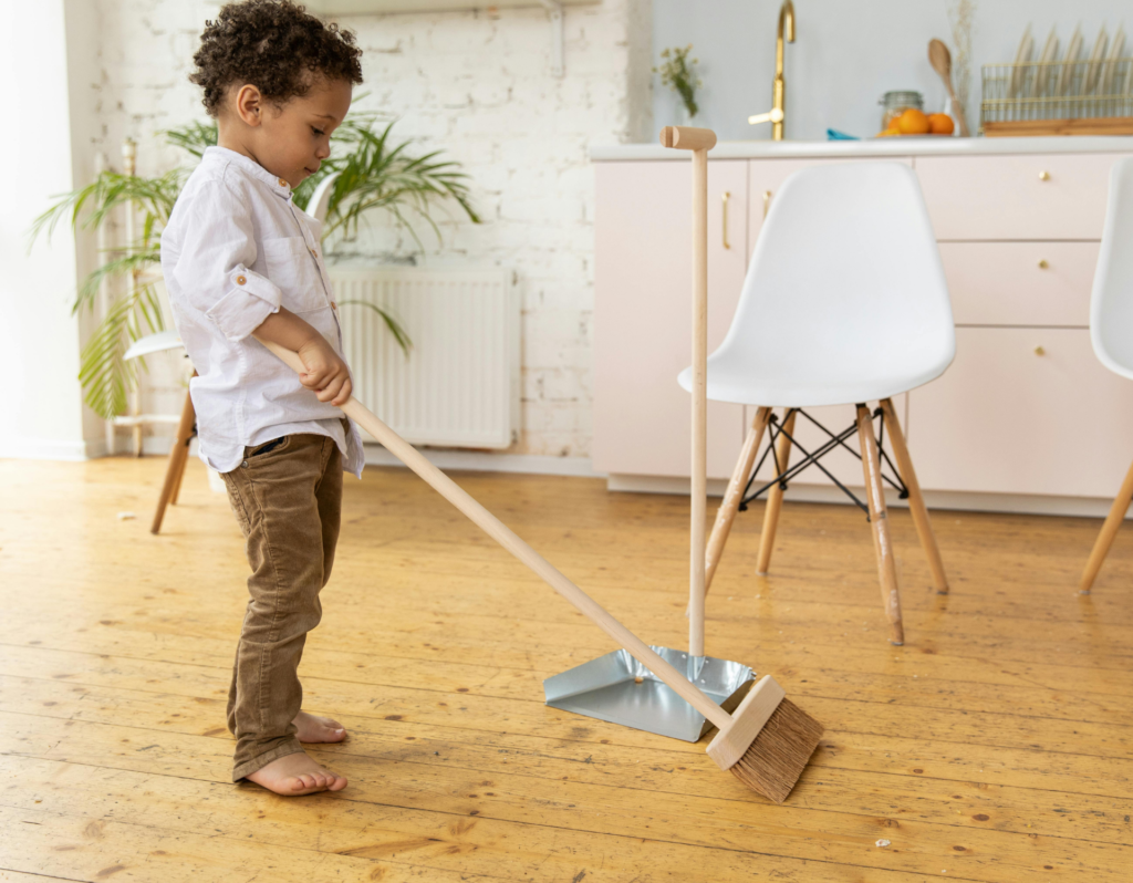 toddler boy cleaning the floor with a broom