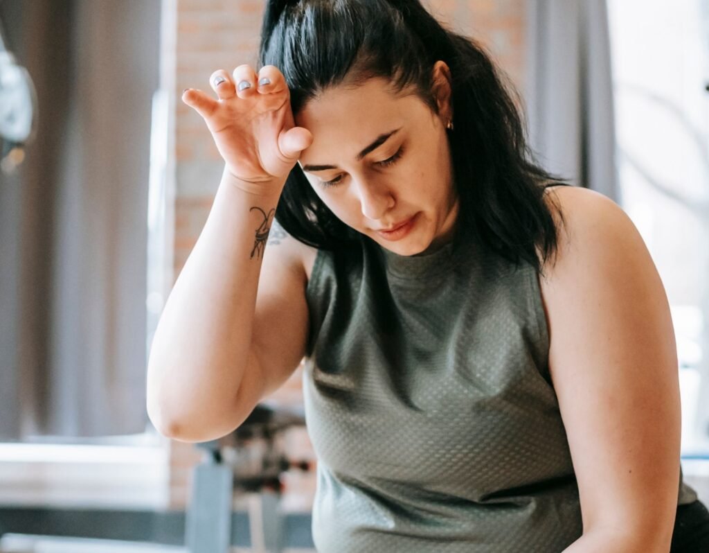 exhausted chronically ill woman with her head to her forehead signaling she doesn't feel well. 