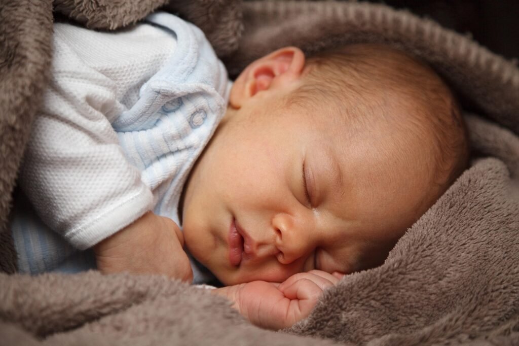 baby boy sleeping wrapped up in a brown blanket