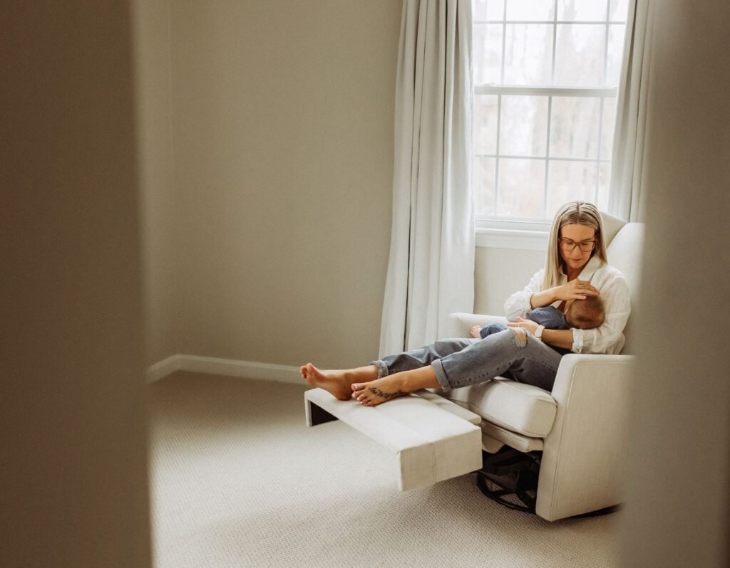 mom breastfeeding baby sitting in an empty room in a chair