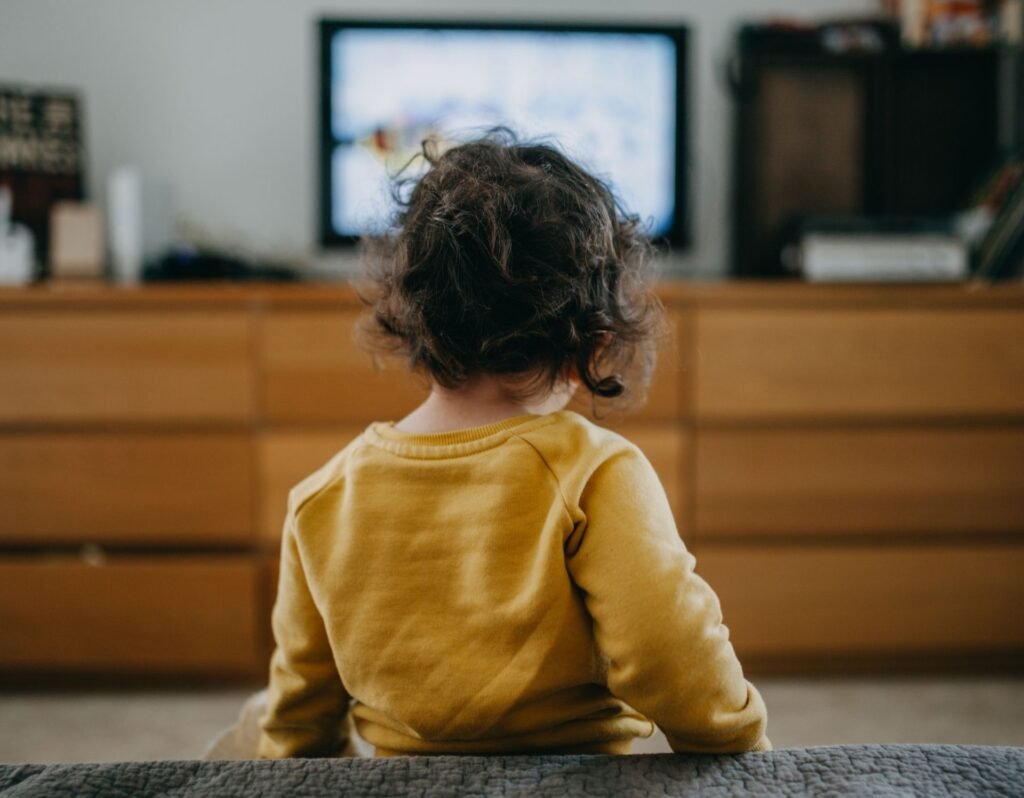 toddler watching TV  wearing yellow shirt, screen time