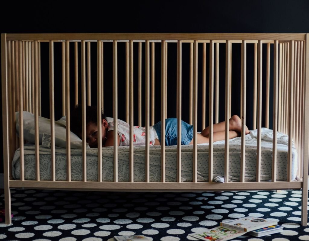 toddlers cry when waking up- toddler laying in dark room in crib