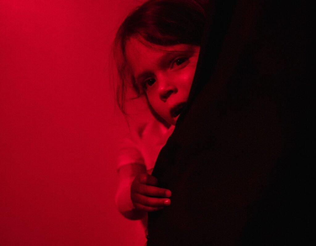 toddler scared hiding behind curtain, red and black duotone photo. Why do Toddlers Cry when they wake up?