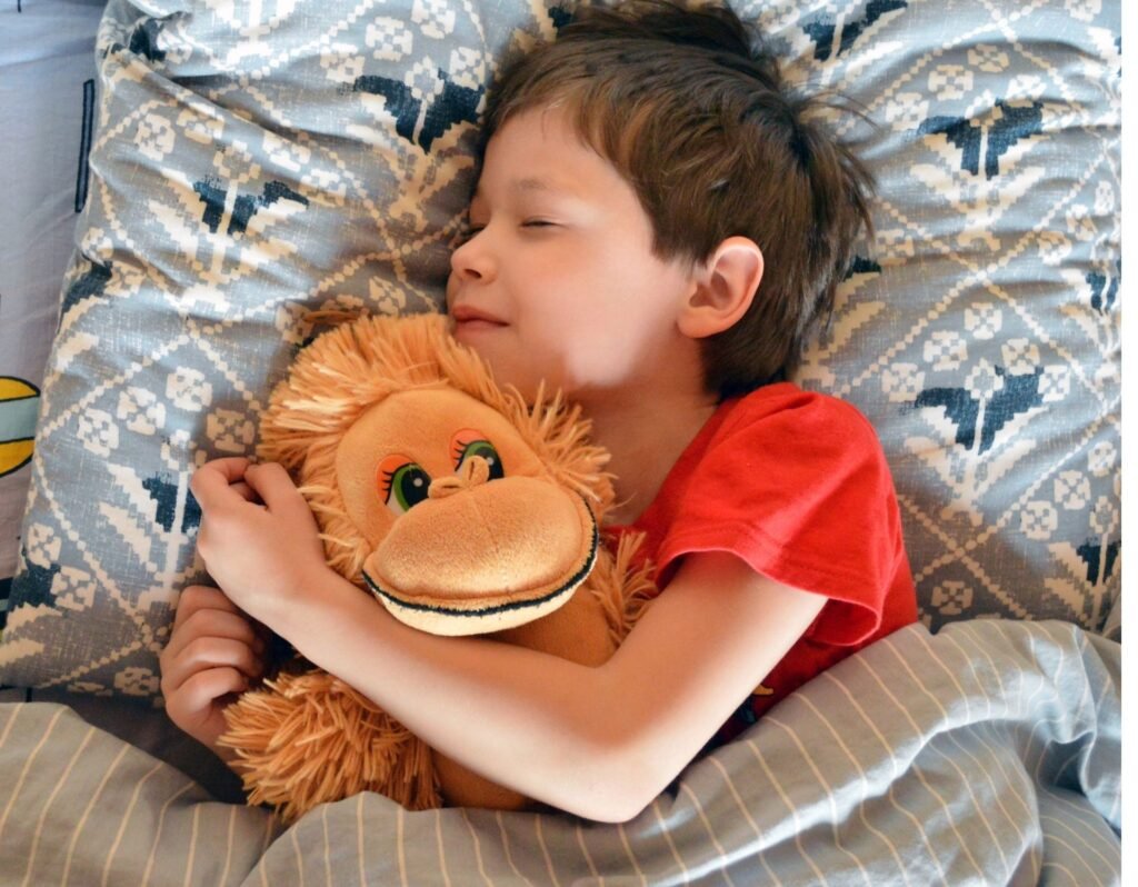 toddler boy cuddling suffed animal monkey sleeping in bed- why toddlers cry when they wake up