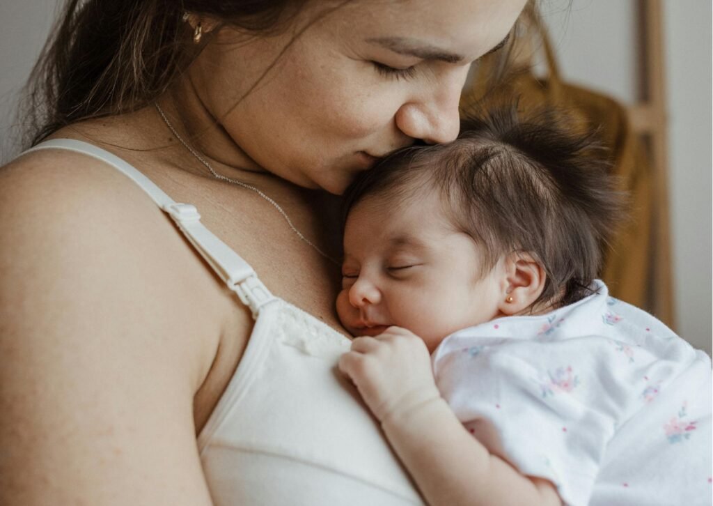 mom kissing babys head. baby resting on moms chest.