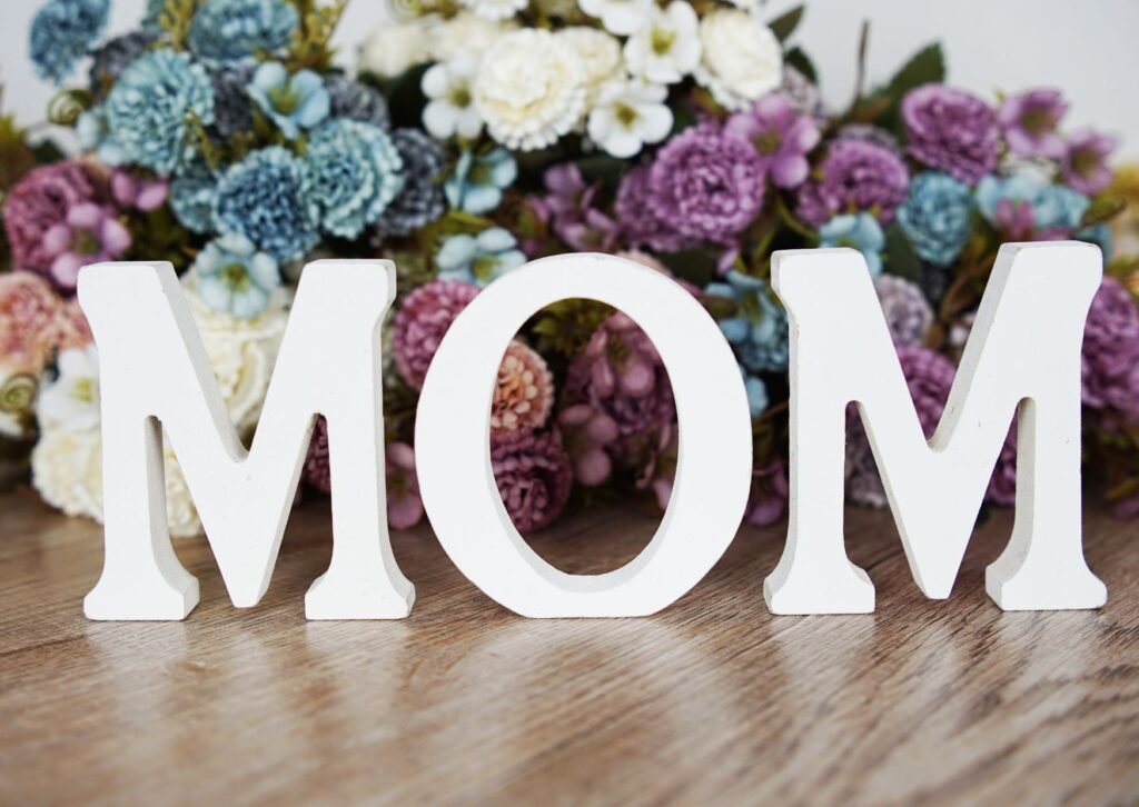 mothers day gift ideas- white wooden letters saying MOM with purple, blue and white roses behind it