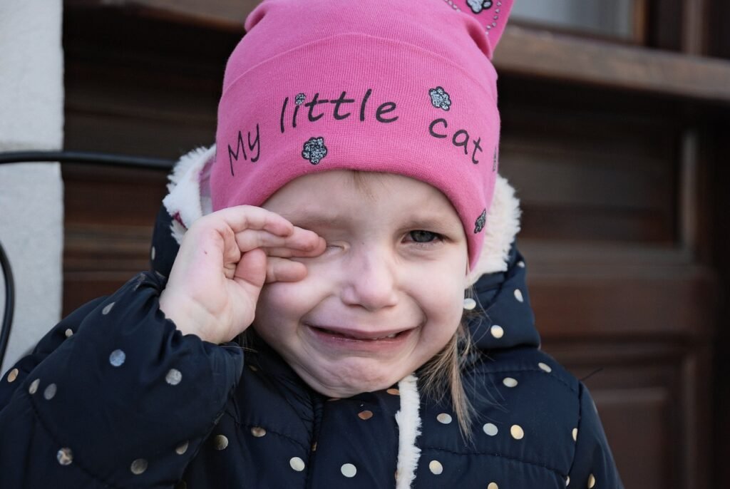 toddler tantrums increase after bringing home new baby- toddler girl crying with one hand on her eye