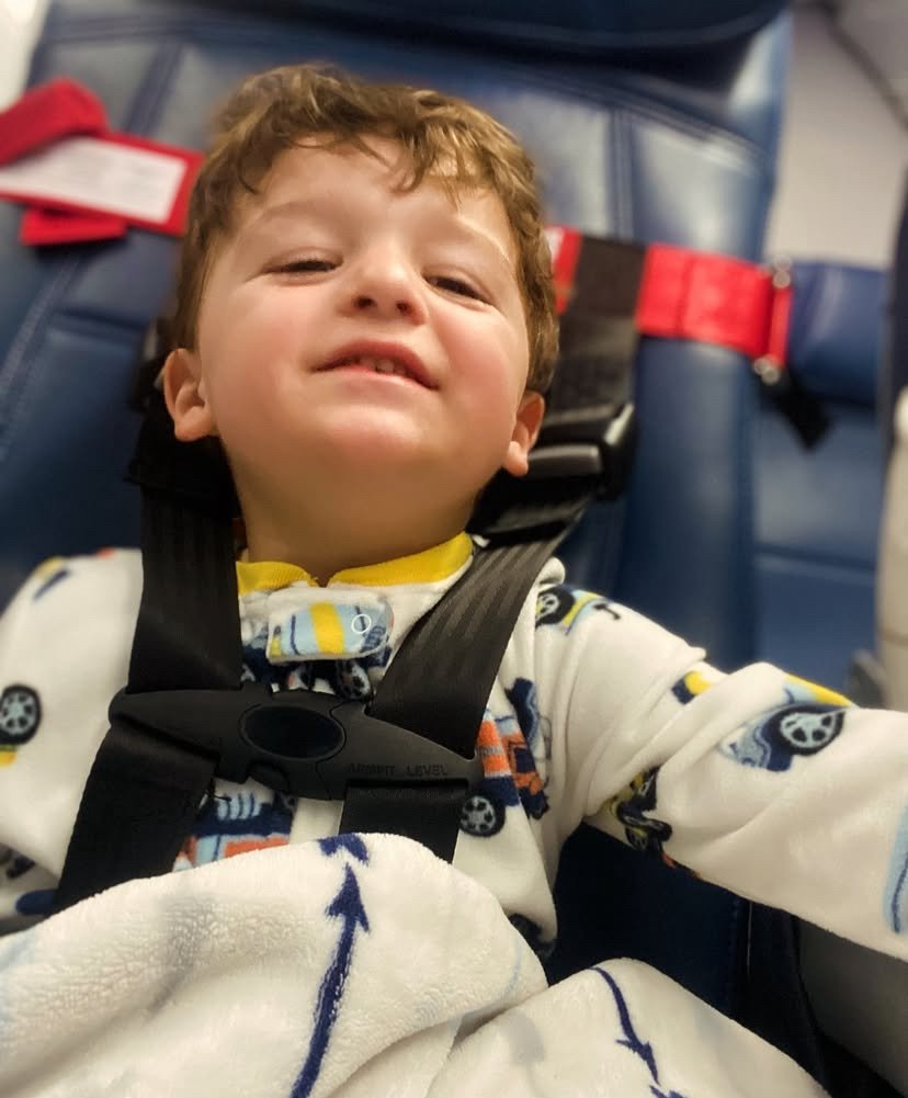 toddler travel essentials- Toddler boy wearing CARES harness on the plane